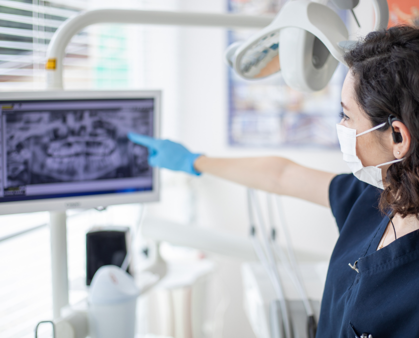 un técnico señalando unas radiografías dentales.