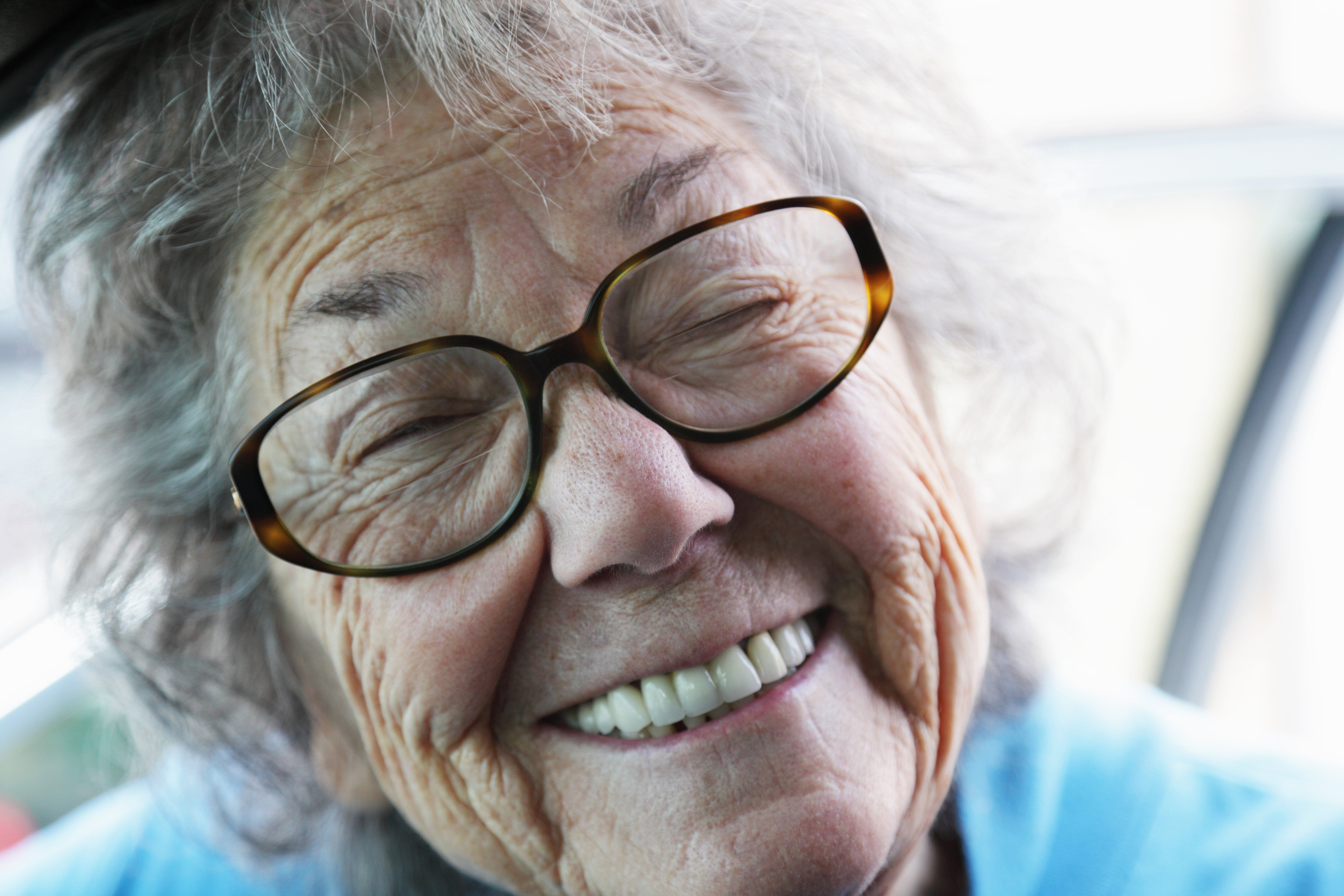 пожилая женщина с зубными протезами улыбается.